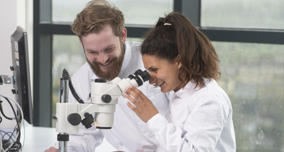 Two lab partners working with a microscope