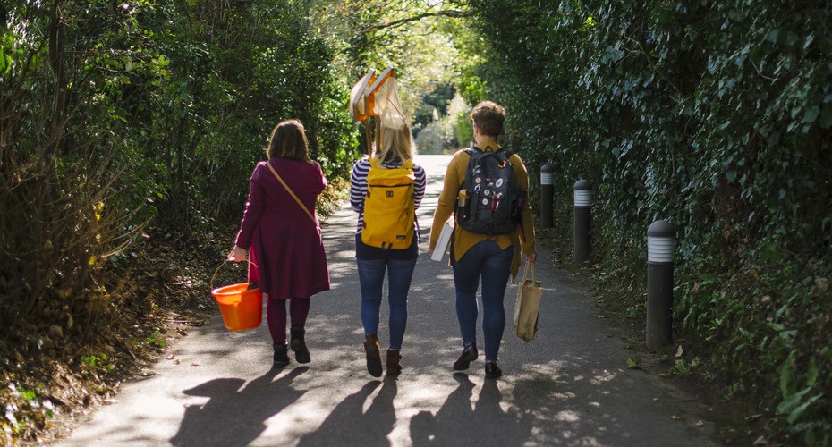 Three Biosciences students walking together, carrying fishing nets and fieldwork equipment