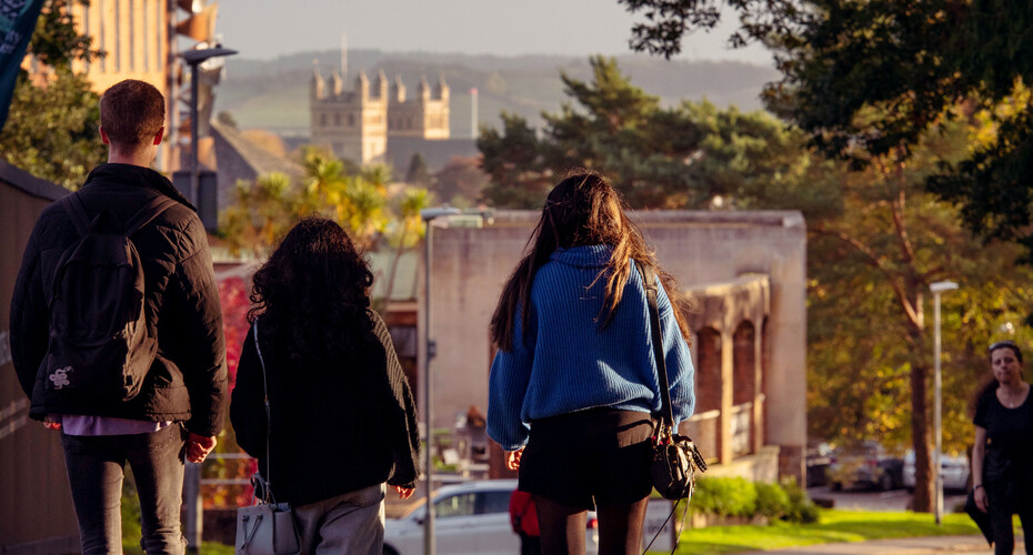 Students walking on Streatham Campus, with a view of Exeter in the distance